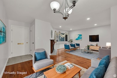 Living area featuring light wood-type flooring, a chandelier, and recessed lighting