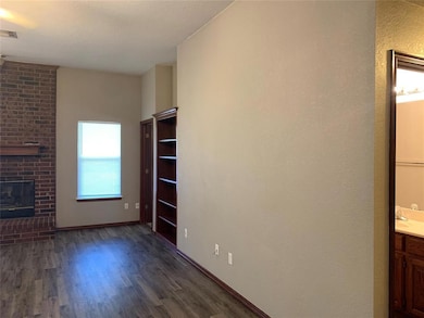 Unfurnished living room with wood finished floors, a fireplace, and baseboards