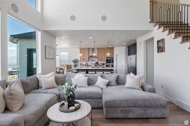 Living room with wood finished floors, recessed lighting, and a high ceiling