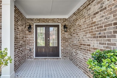 View of exterior entry featuring french doors and brick siding