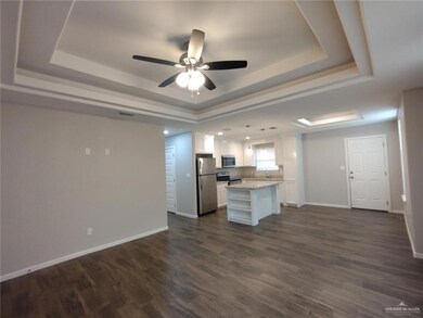 Kitchen with a tray ceiling, stainless steel appliances, white cabinets, baseboards, and a center island