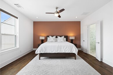 Spacious primary bedroom with hardwood floors, and
