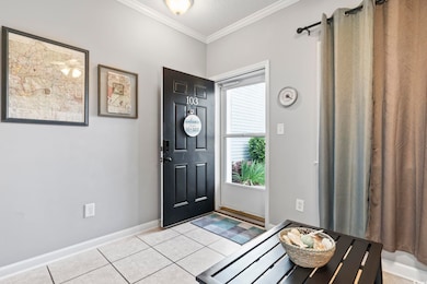 Foyer entrance featuring crown molding, light tile
