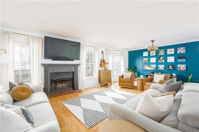 Living area with a fireplace, wood finished floors, and crown molding