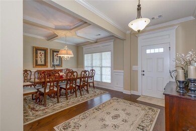 Foyer with crown molding, healthy amount of natural light, dark wood-style floors, wainscoting, and beam ceiling