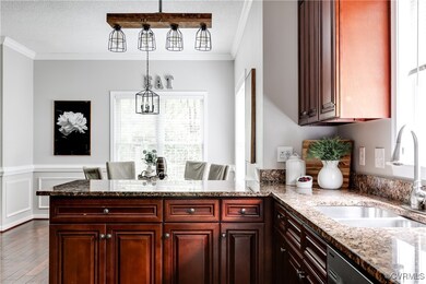 This inviting kitchen view highlights the striking modern light fixtures, continued rich wood cabinetry, and elegant granite countertops, creating a perfect blend of warmth and contemporary style