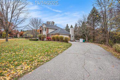 View of front of property featuring a chimney, driveway, a front yard, a garage, and brick siding