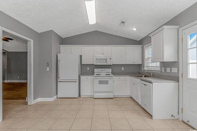 Kitchen featuring white appliances, lofted ceiling