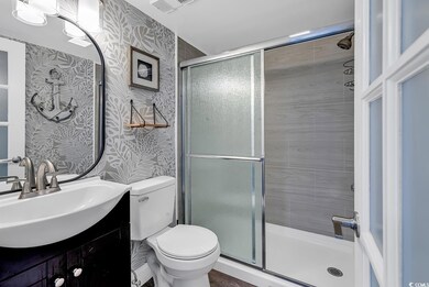 Bathroom featuring vanity, toilet, and a shower wi