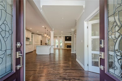 Entryway featuring crown molding, dark wood-style floors, a fireplace with raised hearth, and recessed lighting