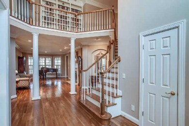 Grand entry. Notice the hardwood floors - they are everywhere. Upstairs bookshelves lends a cozy library feel to this warm and gracious home. Door on right to powder room. See too the picture niche beyond the stairs.