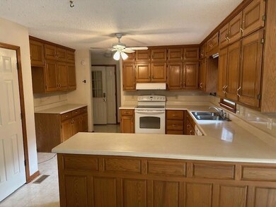 Kitchen featuring white range with electric stovetop, a sink, under cabinet range hood, a ceiling fan, and light countertops