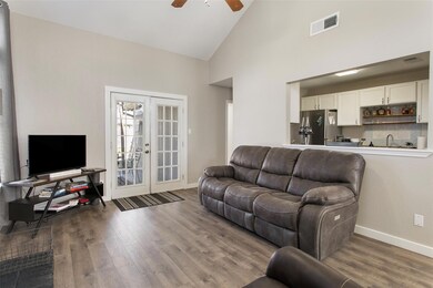 Living room with dark hardwood / wood-style floors, high vaulted ceiling, french doors, and ceiling fan