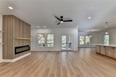 Unfurnished living room featuring light wood-style flooring, a glass covered fireplace, recessed lighting, ceiling fan, and french doors