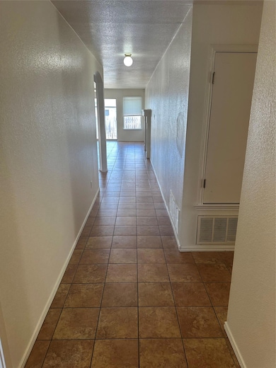 Hall featuring a textured wall, tile patterned flooring, a textured ceiling, and arched walkways