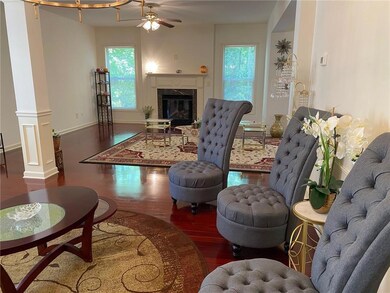 Living area with wood finished floors, a premium fireplace, ceiling fan, decorative columns, and baseboards