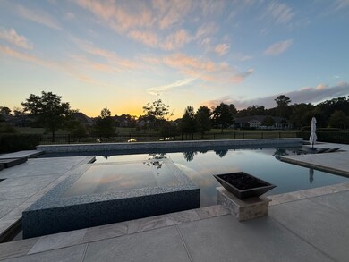 The backyard oasis as the sun sets.  The custom pool also boasts sheer descent water features along the stacked stone edge as well as gas fire bowls.