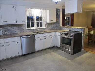 Kitchen updated with glass subway style backsplash, lighting fixture, quartz countertop and breakfast bar, refinished cabinets, linoleum flooring, and stainless-steel appliances, smooth top stove replaced 2023. 6 metal sliding pull out drawers added to cabinetry.