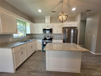 Kitchen with a sink, stainless steel appliances, white cabinets, visible vents, and a kitchen island