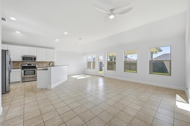 Kitchen featuring white cabinets, light tile patterned floors, appliances with stainless steel finishes, dark countertops, and tasteful backsplash