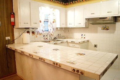 Kitchen with tile countertops, white cabinets, dec