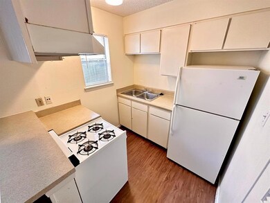 Kitchen with white appliances, light countertops, a textured ceiling, dark wood-style flooring, and white cabinets