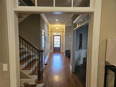 Foyer entrance with dark wood-style floors, crown molding, and stairway