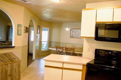 Kitchen with decorative light fixtures, white cabinetry, black appliances, kitchen peninsula, and tile floors