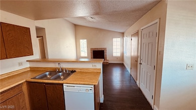 Kitchen featuring white dishwasher, a sink, vaulte