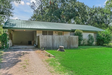 View of front of house with driveway, brick siding, a metal roof, a front lawn, and an attached carport