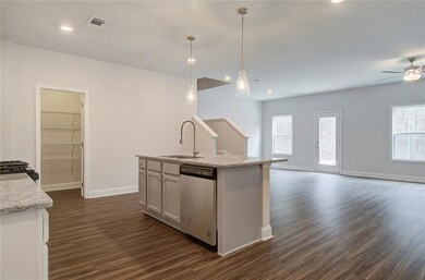 Kitchen featuring hanging light fixtures, light stone counters, dark wood finished floors, stainless steel dishwasher, and recessed lighting