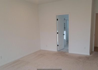 Empty room with light colored carpet and baseboar