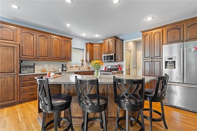 Kitchen featuring stainless steel appliances, dark stone counters, a kitchen island, light wood finished floors, and a breakfast bar area