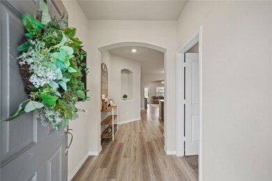 Hallway with arched walkways, baseboards, and ligh
