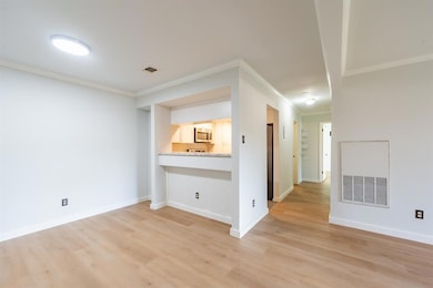 Empty room with crown molding and light wood finished floors