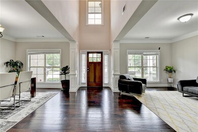 Foyer featuring decorative columns, healthy amount of natural light, dark wood-style floors, and ornamental molding