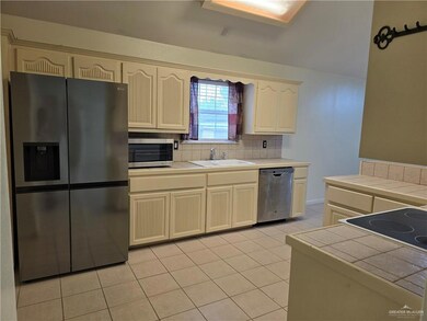 Kitchen featuring sink, tasteful backsplash, light tile floors, tile countertops, and appliances with stainless steel finishes