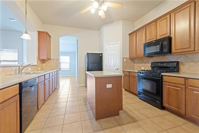 Kitchen with black appliances, arched walkways, a