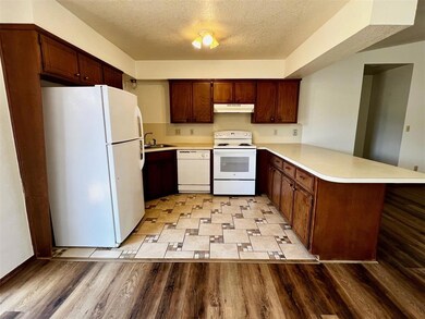 Kitchen featuring white appliances, a textured cei