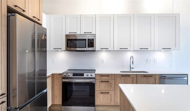 Kitchen with a sink, light countertops, white cabinetry, stainless steel appliances, and decorative backsplash