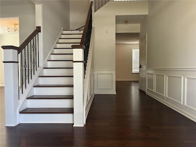 Staircase featuring wood-type flooring, wainscoting, a towering ceiling, and a decorative wall