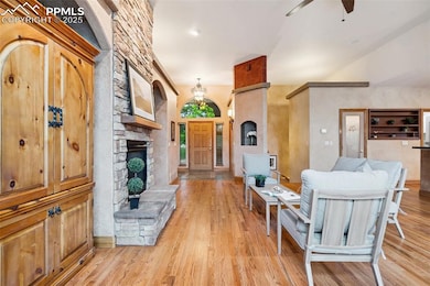 Living room featuring hardwood floors, ceiling fan, a fireplace, and a chandelier