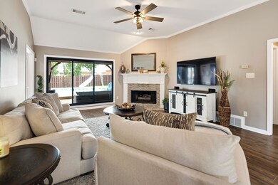 Living room with lofted ceiling, dark wood finished floors, a ceiling fan, a fireplace, and crown molding