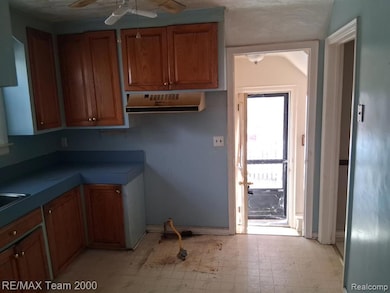 Kitchen featuring light floors, brown cabinetry, ceiling fan, and ventilation hood