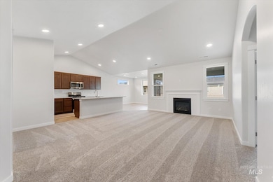 Unfurnished living room featuring light carpet, lofted ceiling, a glass covered fireplace, and recessed lighting