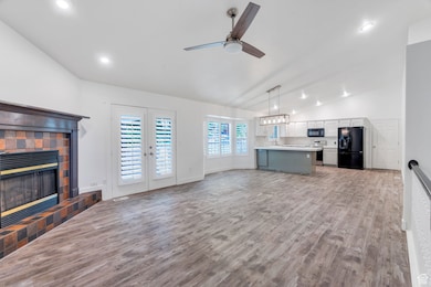 Unfurnished living room with vaulted ceiling, wood finished floors, french doors, recessed lighting, and a ceiling fan
