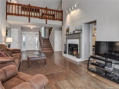 View of living room facing door with loft area abo