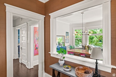 Entrance foyer featuring ornamental molding, a chandelier, and dark wood-style flooring