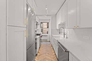 Kitchen with light stone counters, white cabinetry, premium appliances, and exhaust hood