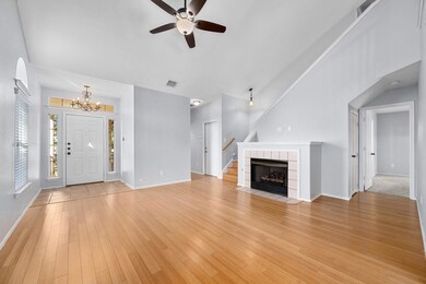 Unfurnished living room with a ceiling fan, light wood-type flooring, high vaulted ceiling, stairway, and arched walkways